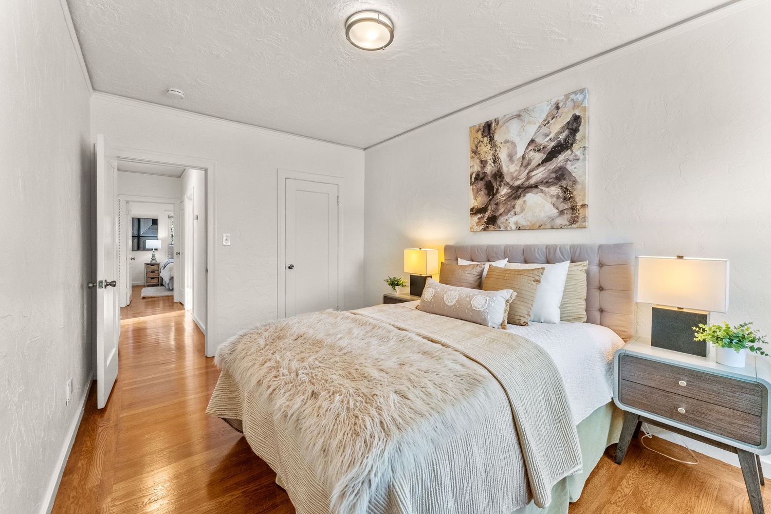 Interior of a clean bedroom with hardwood floors, exposed brick, and natural light.