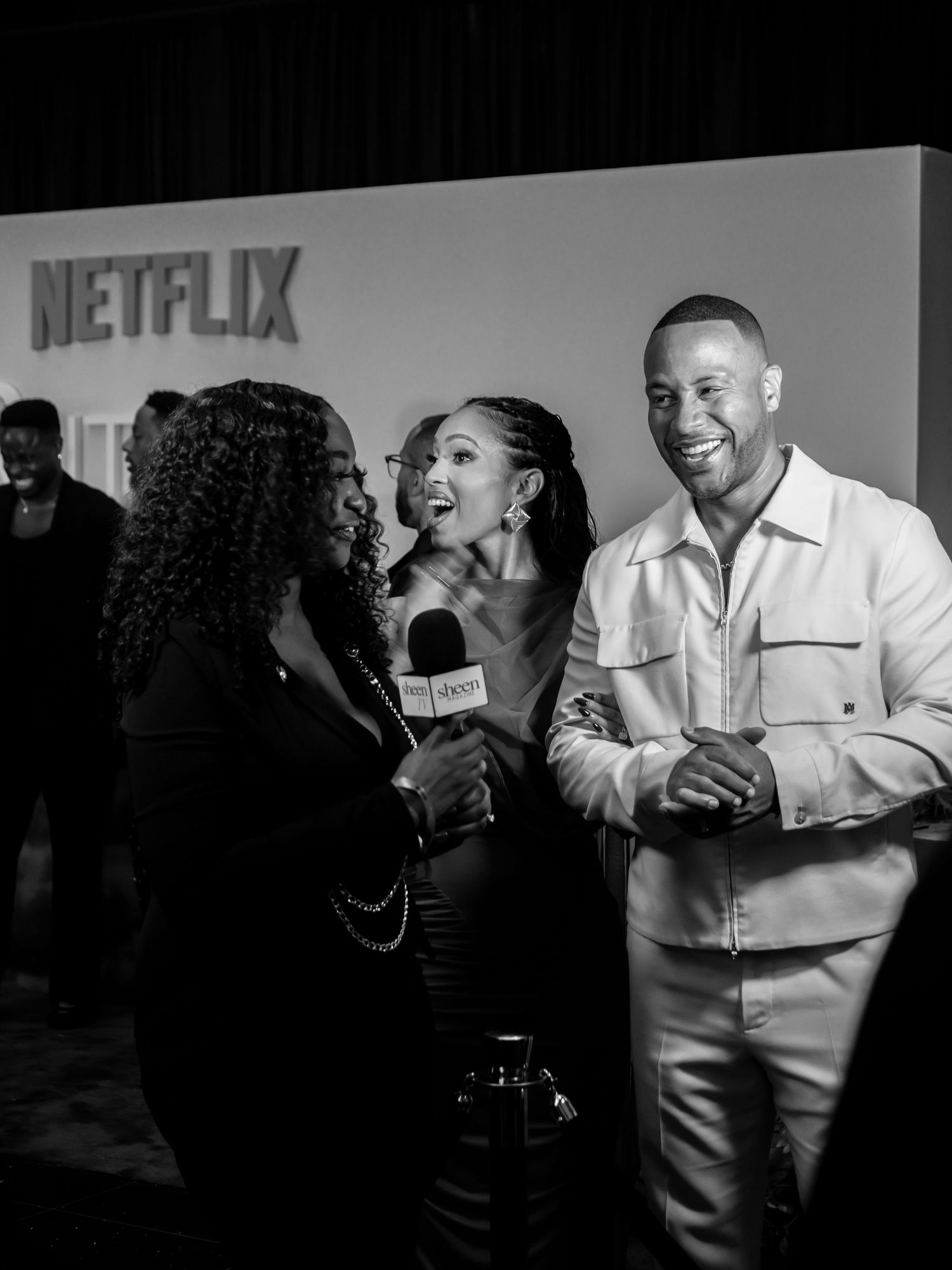 Guests mingle and laugh at a Netflix event with dramatic lighting and a festive atmosphere.