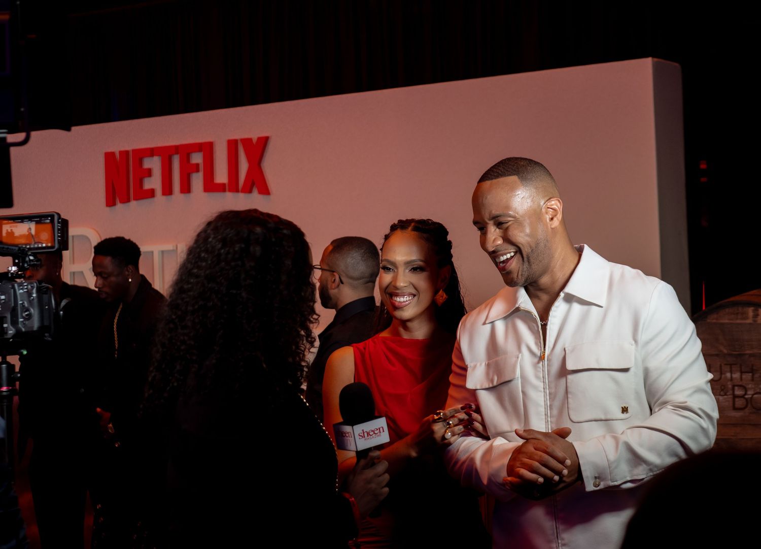 Red-lit Netflix event with crowd and photographers in dark atmosphere.