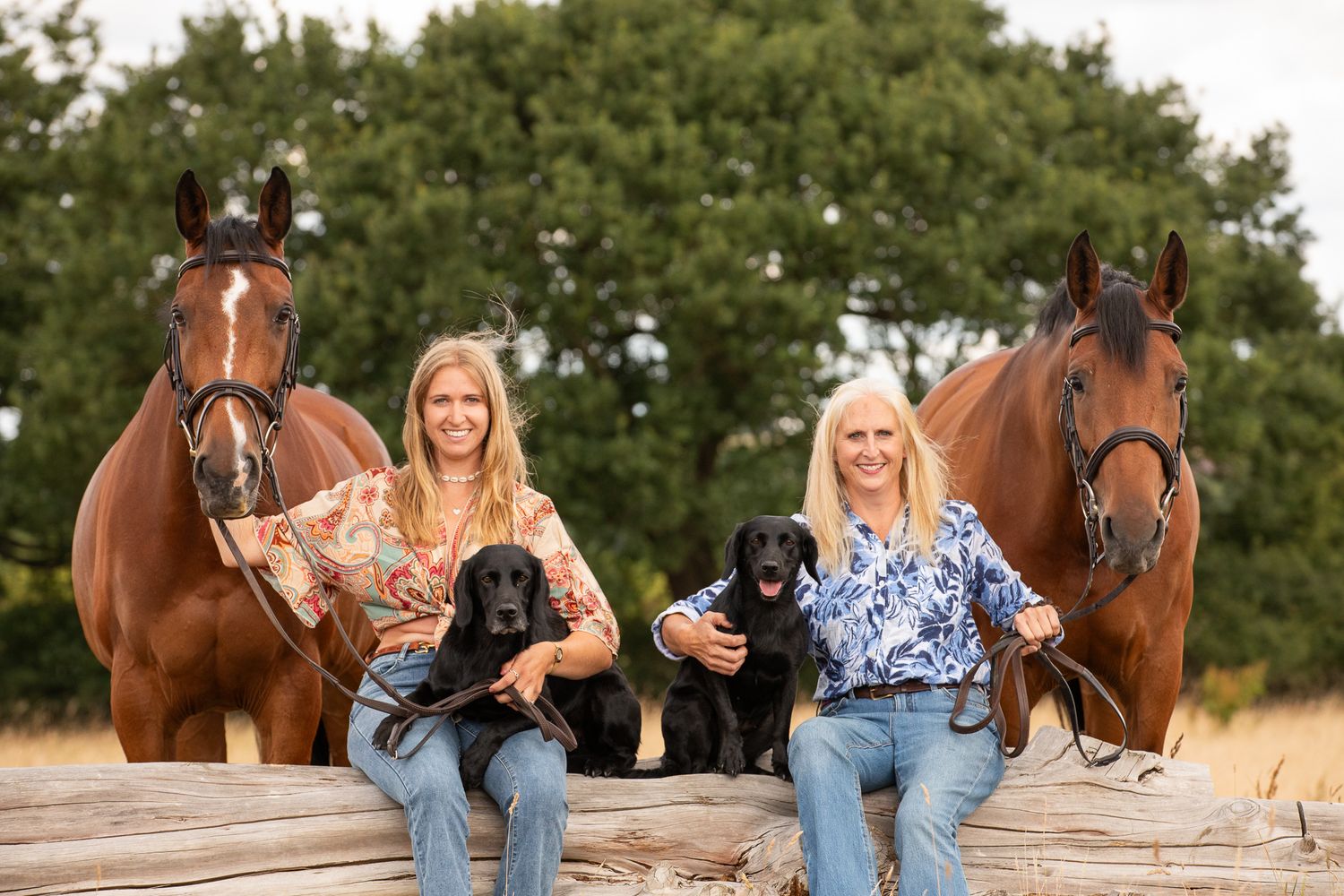 A group poses with horses along a tree-lined path during a sunny autumn day for outdoor photos.