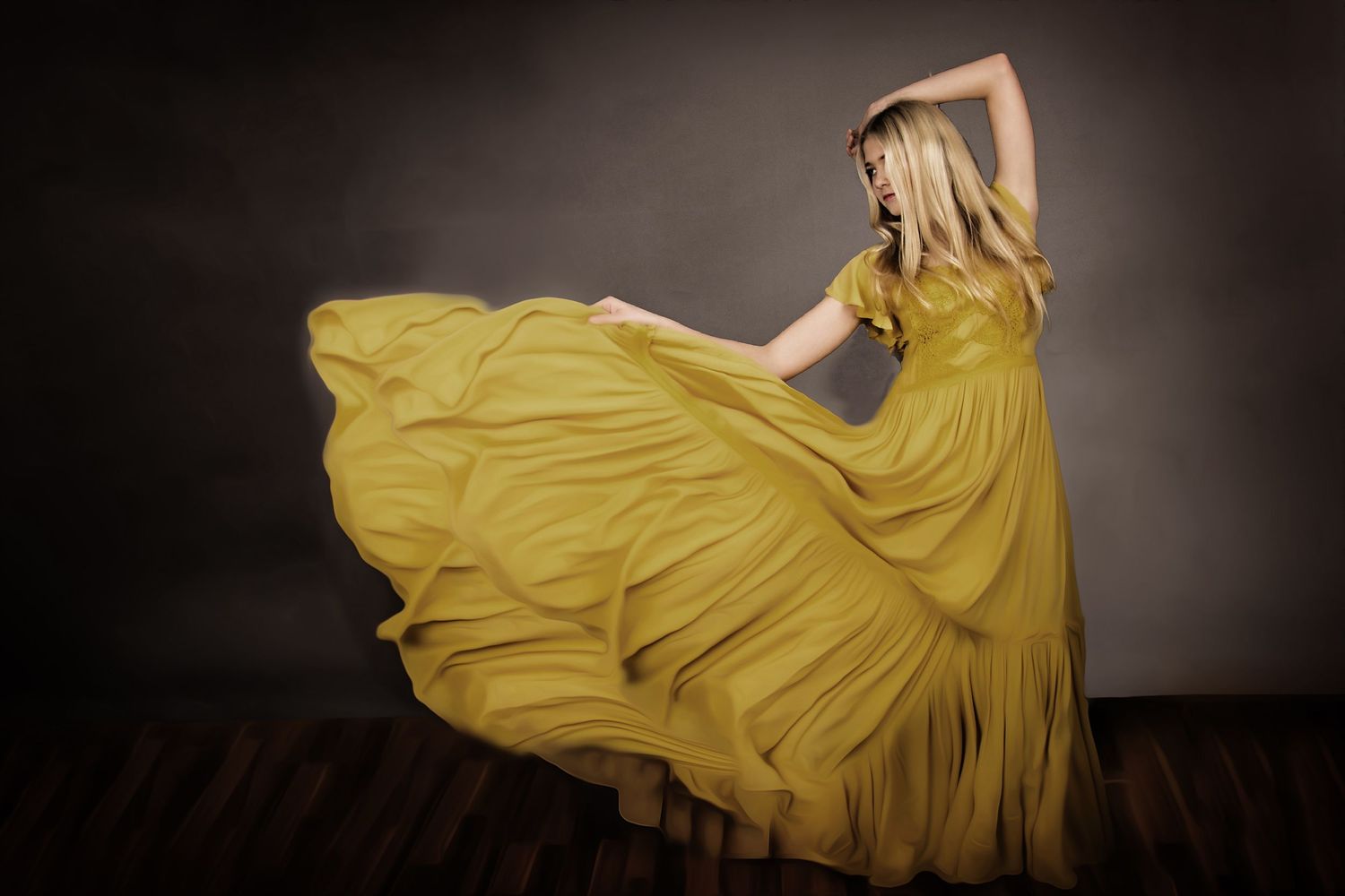 A flowing yellow gown twirls dramatically against a dark background creating an artistic motion portrait.