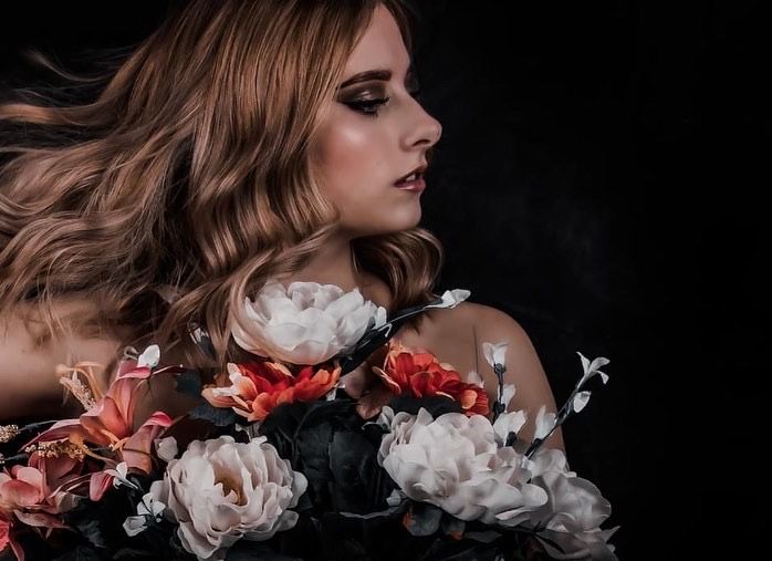 Moody portrait with dramatic smoky effect and rose floral elements against dark background.