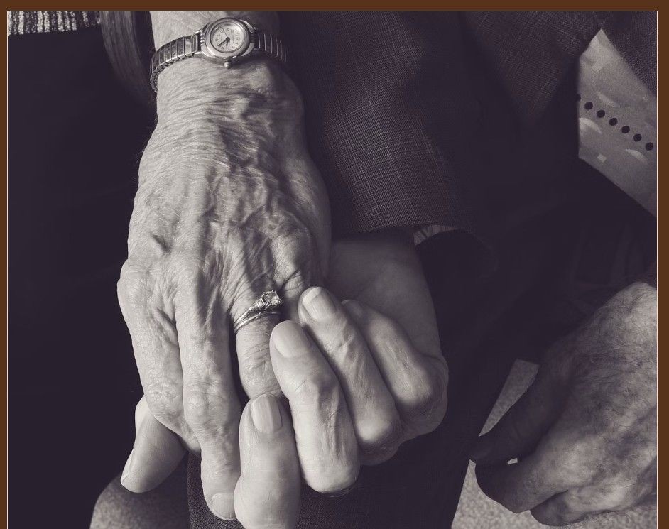 Black and white close-up photograph of elderly hands with wrinkled skin and visible veins.