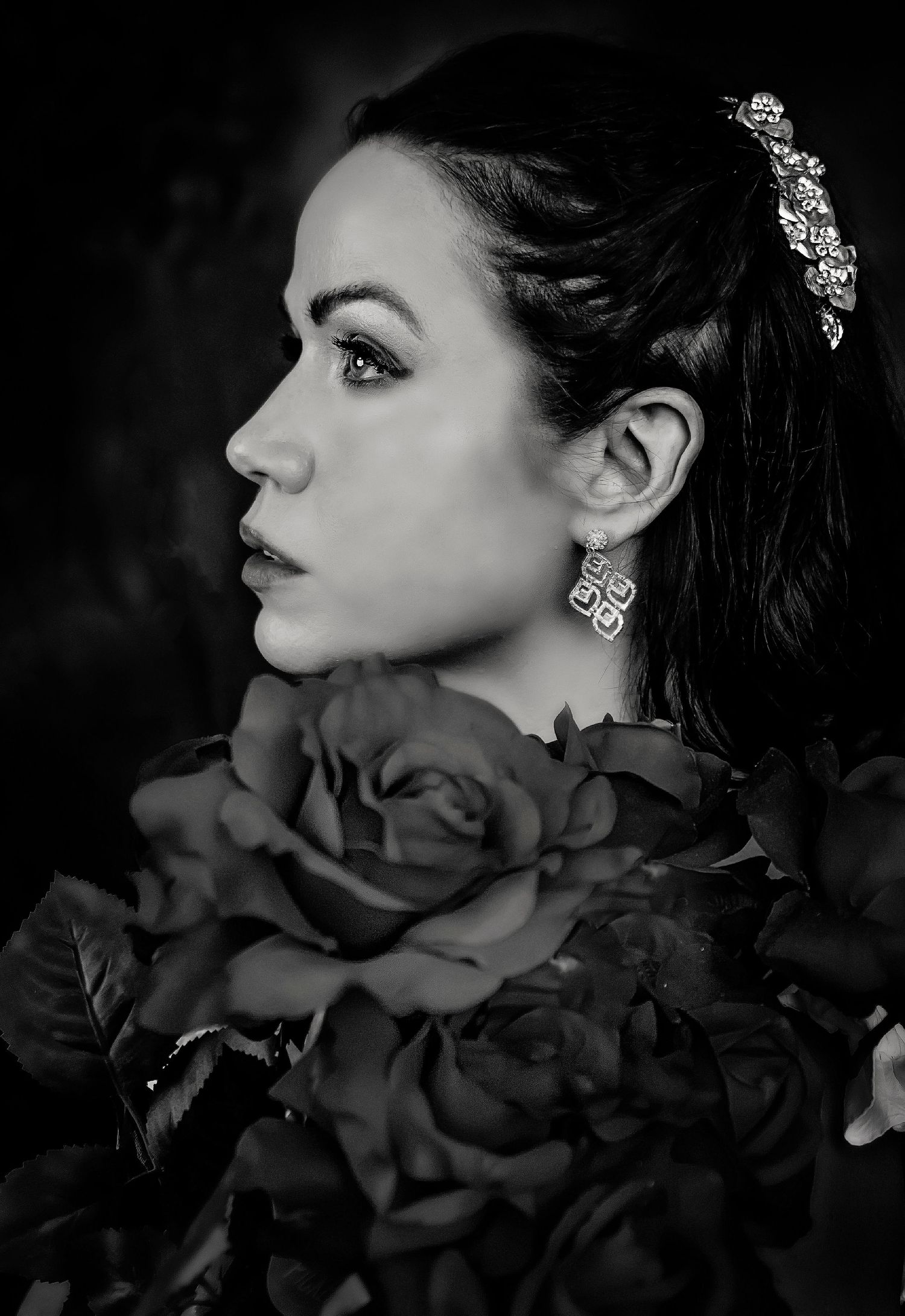Dramatic black and white profile portrait with roses and crystal hair accessory.