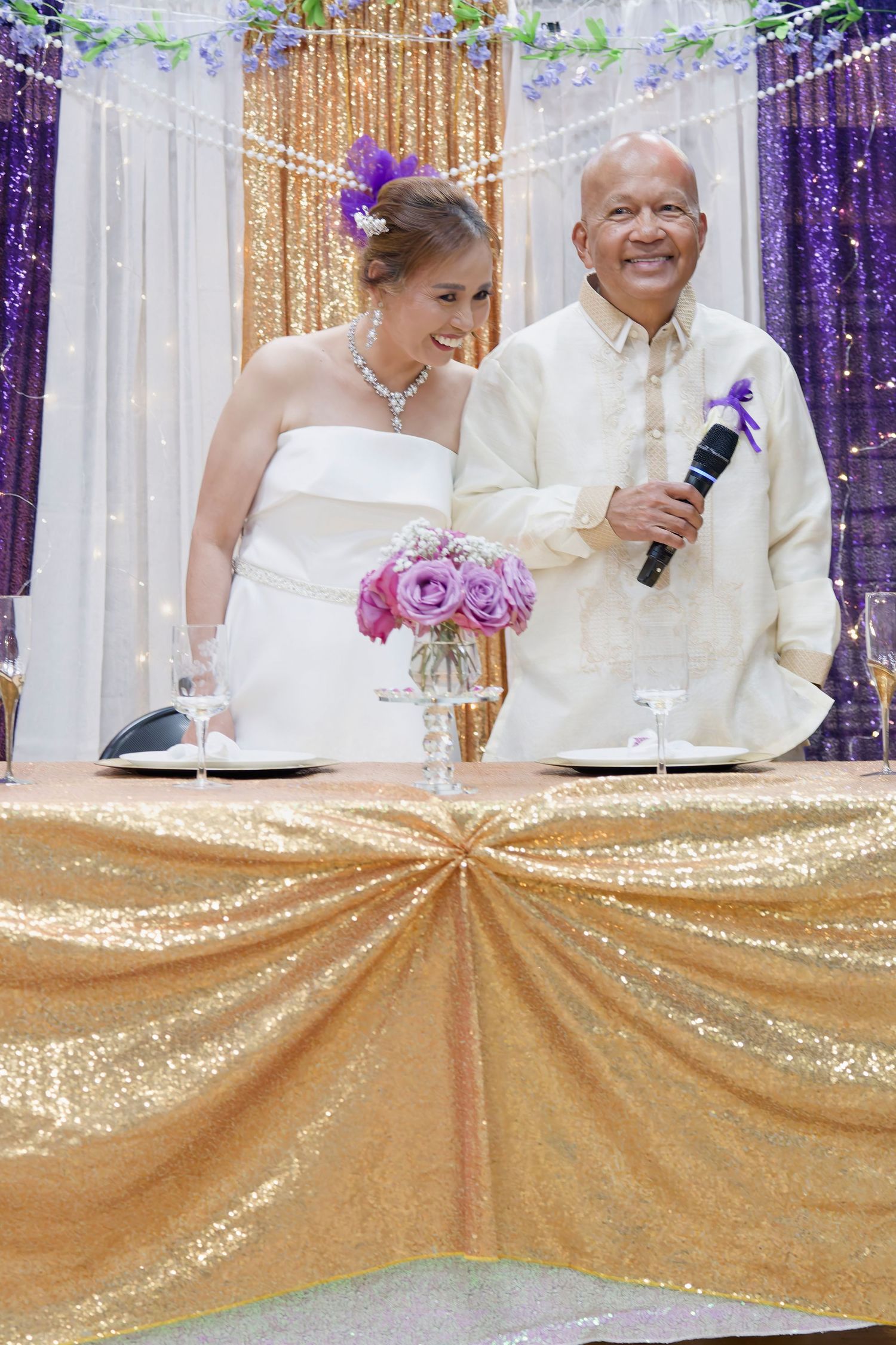 A wedding couple shares tender moments during their celebration beneath white flowing fabric decor.