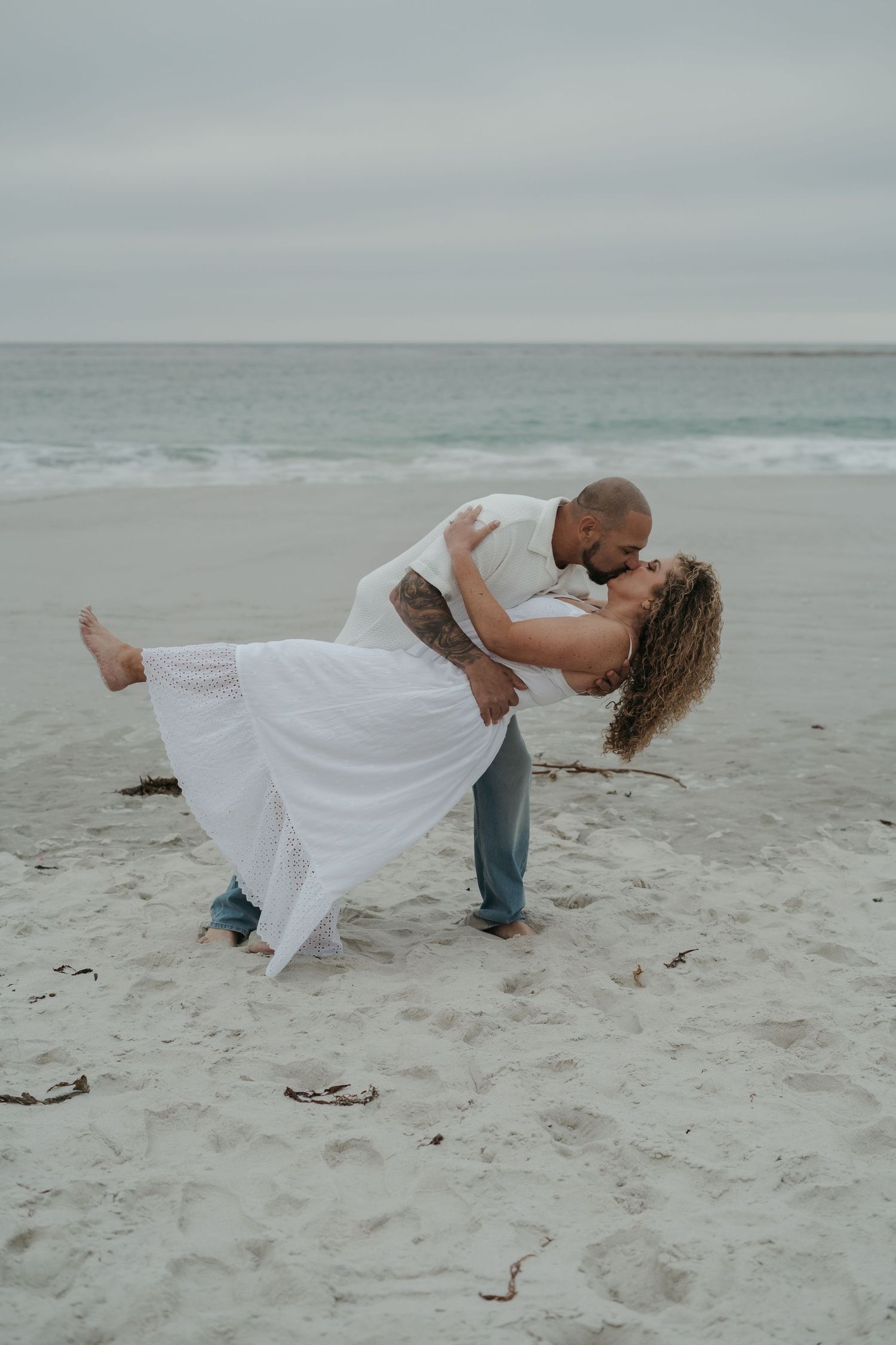 A romantic dance dip pose sequence on a stormy beach, showing a couple in white dress and casual wear against gray skies.