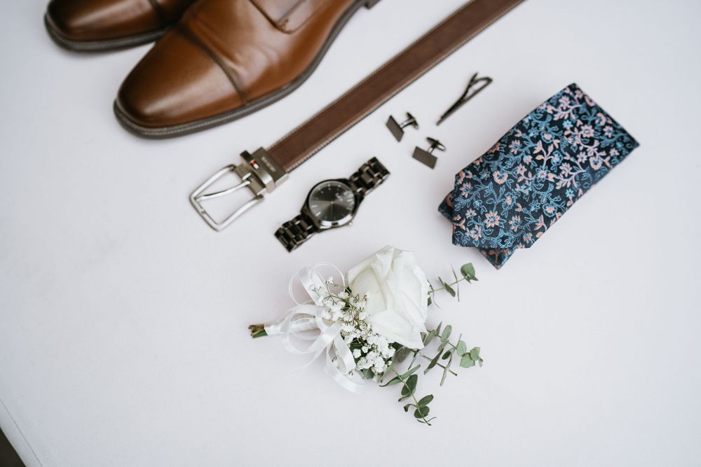 Brown leather dress shoes and accessories arranged on a white background.