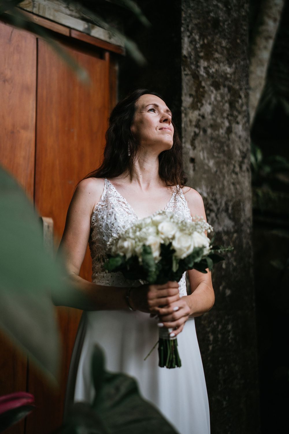 An elegant bridal portrait with white bouquet against natural wooden backdrop.