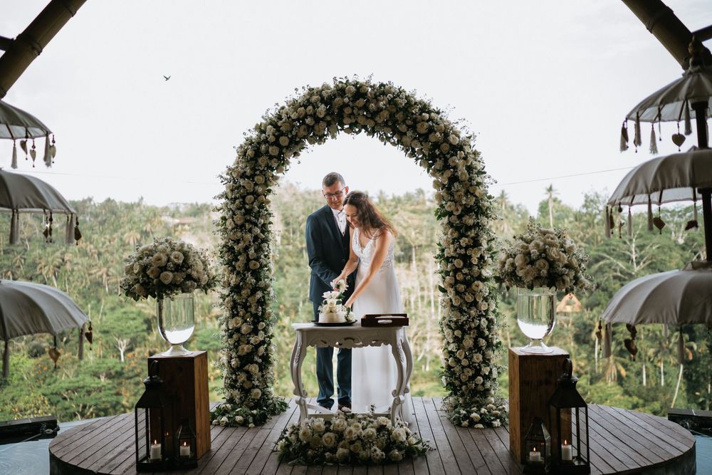 A wedding ceremony setup featuring a stunning floral arch overlooking a scenic landscape.