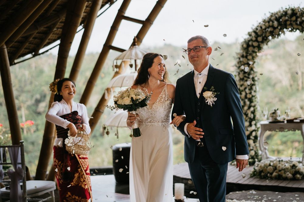 Wedding celebration moments captured under a rustic wooden pavilion decorated with floral arrangements.