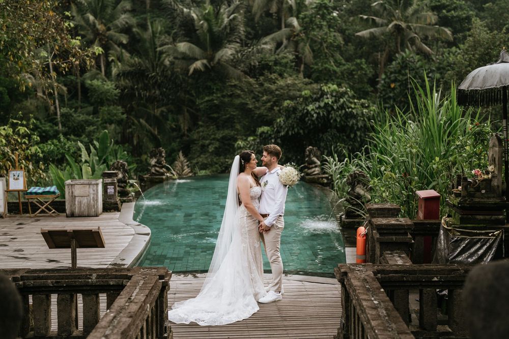 Wedding ceremony taking place on a wooden deck surrounded by tropical greenery.