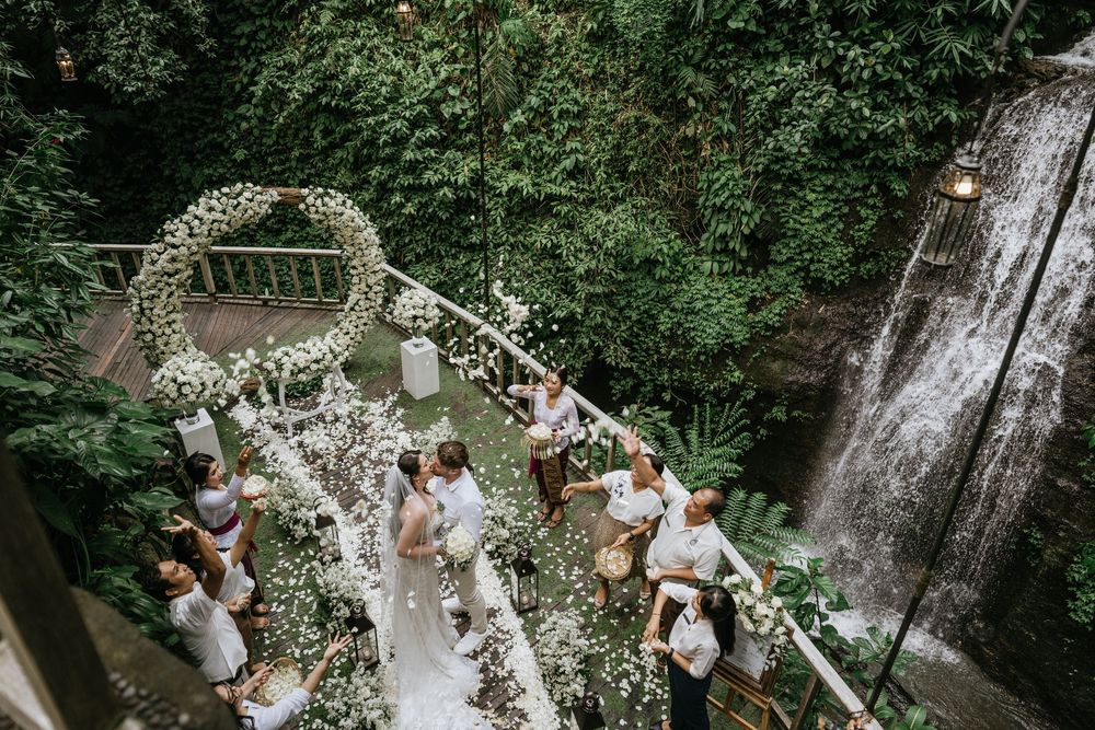 Overhead shot of a garden wedding ceremony with white floral arch and natural surroundings.