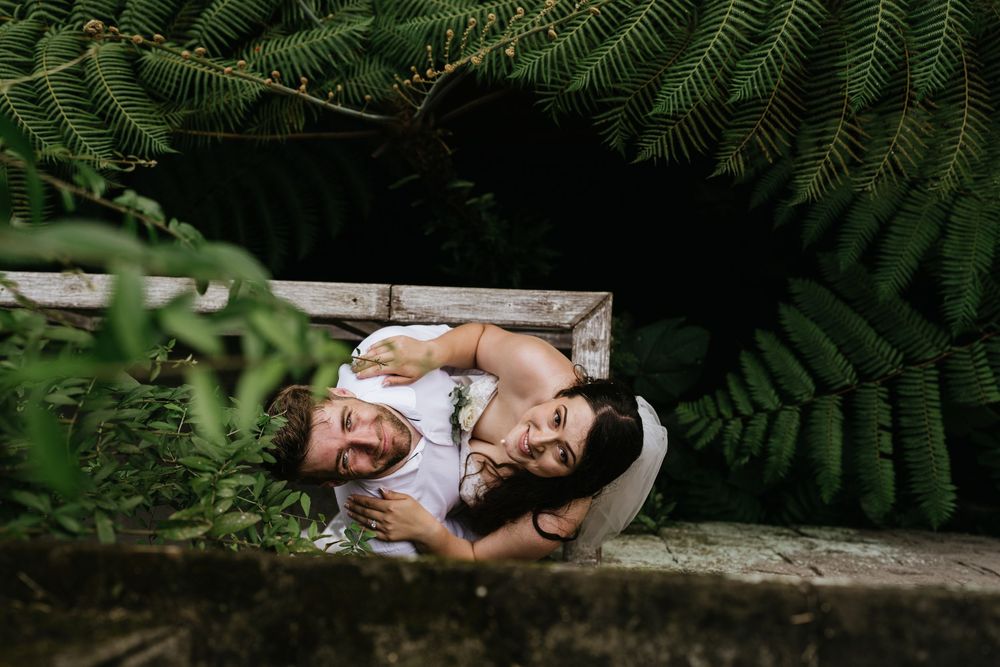 Lush ferns frame a romantic wedding scene in a tropical garden setting.