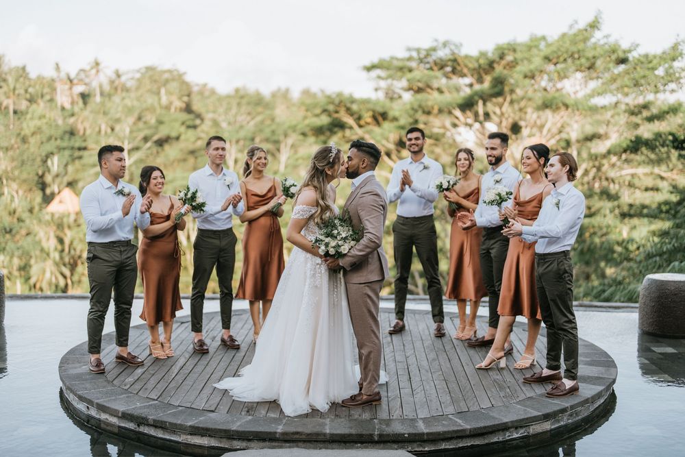 Wedding party poses on a wooden deck platform with scenic forest backdrop.