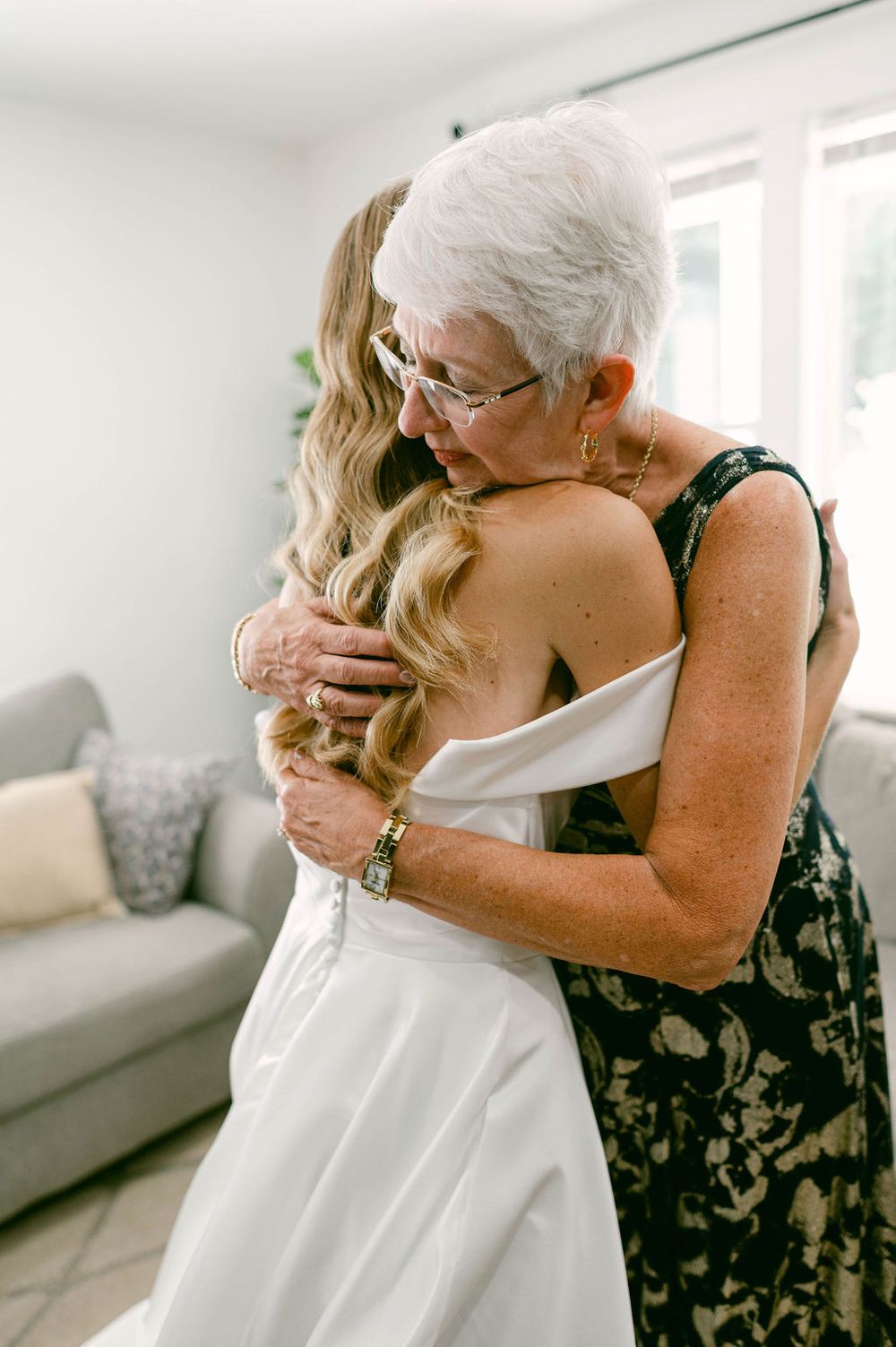 Emotional wedding day embrace between two people in white dress and floral print.