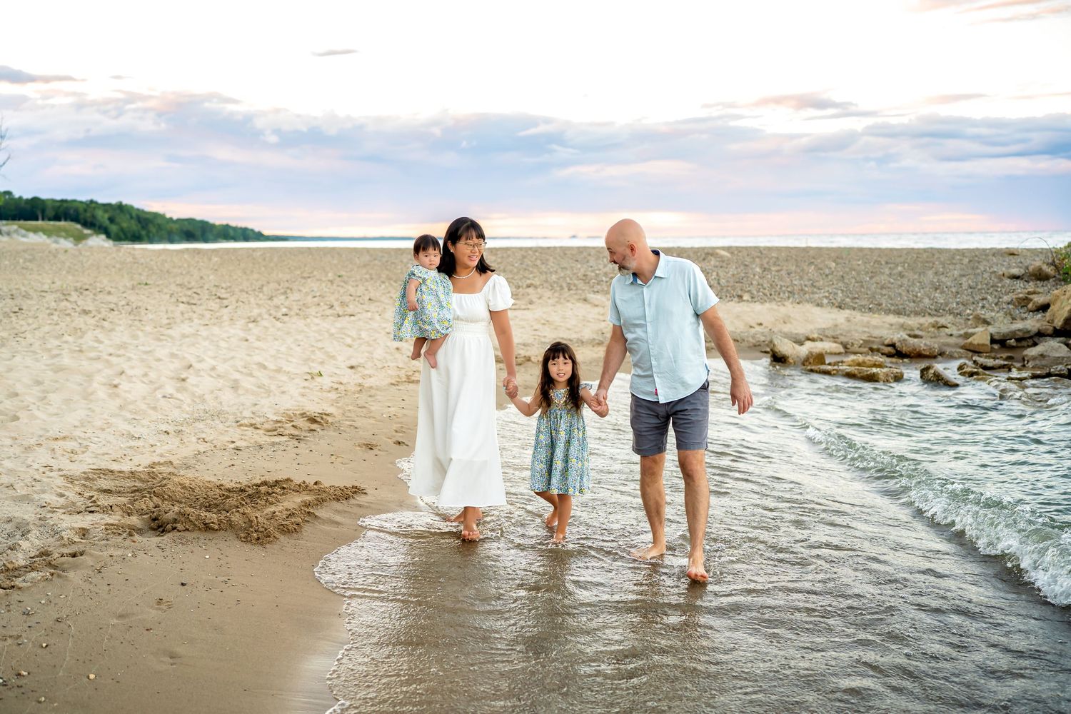 A family enjoying a warm summer day wading and splashing in the shallow ocean waters along a sandy beach.