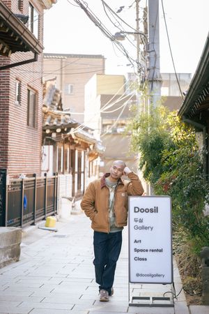 Urban street scene with art gallery signage and traditional Korean architectural elements.