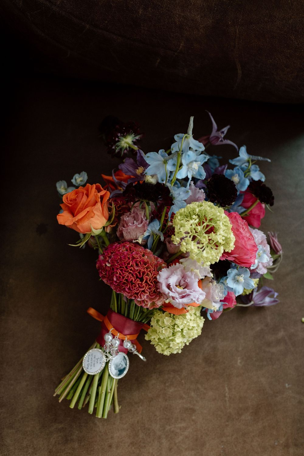 Wedding bouquet arrangements featuring colourful blooms of pinks, oranges, and chartreuse against dark background.