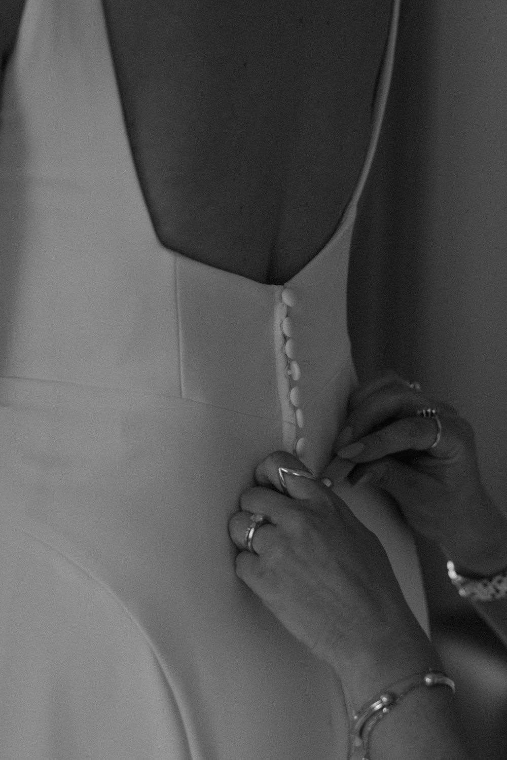 Bride has her wedding dress buttoned up before her ceremony.