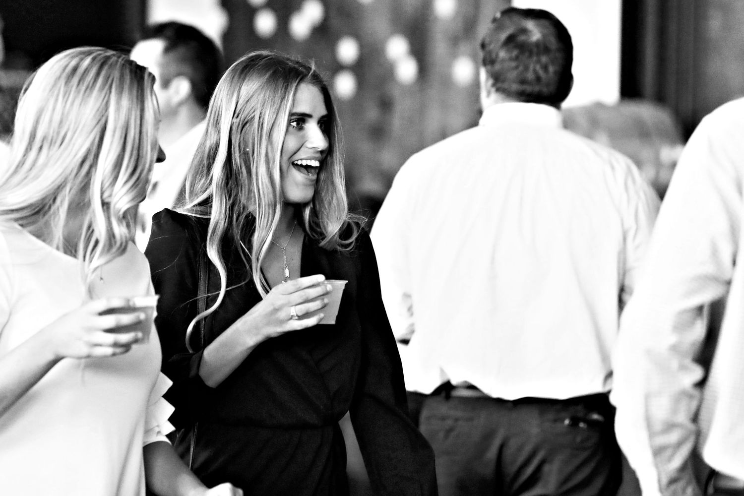 A lively crowd of people mingling and laughing at an upscale social gathering.
