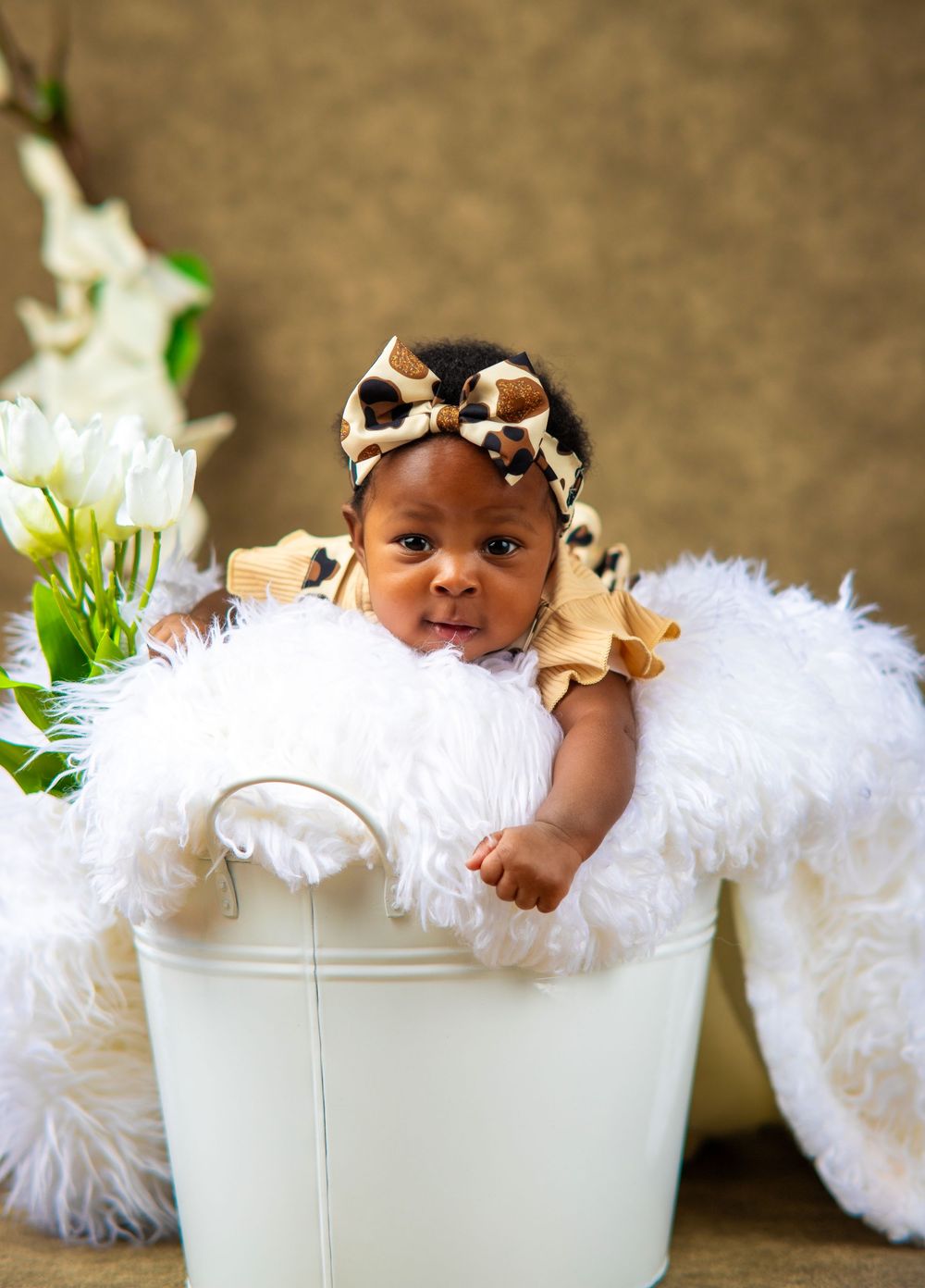 Sweet baby portrait in white bucket prop with delicate white decorative elements.