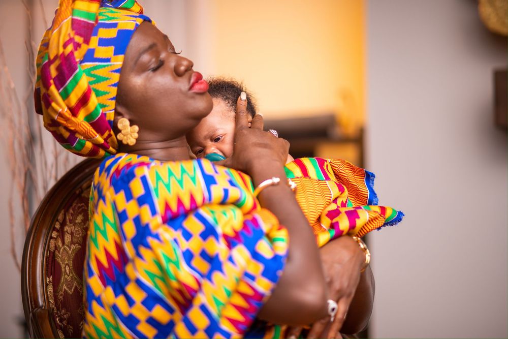 Vibrant traditional African headwrap in colorful kente print shown in profile against warm lighting.