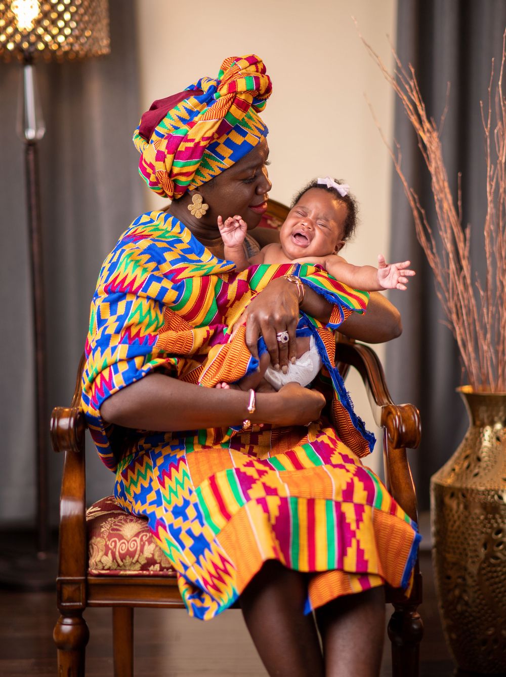 Joyful dance movements in bright kente print clothing captured against an indoor setting.