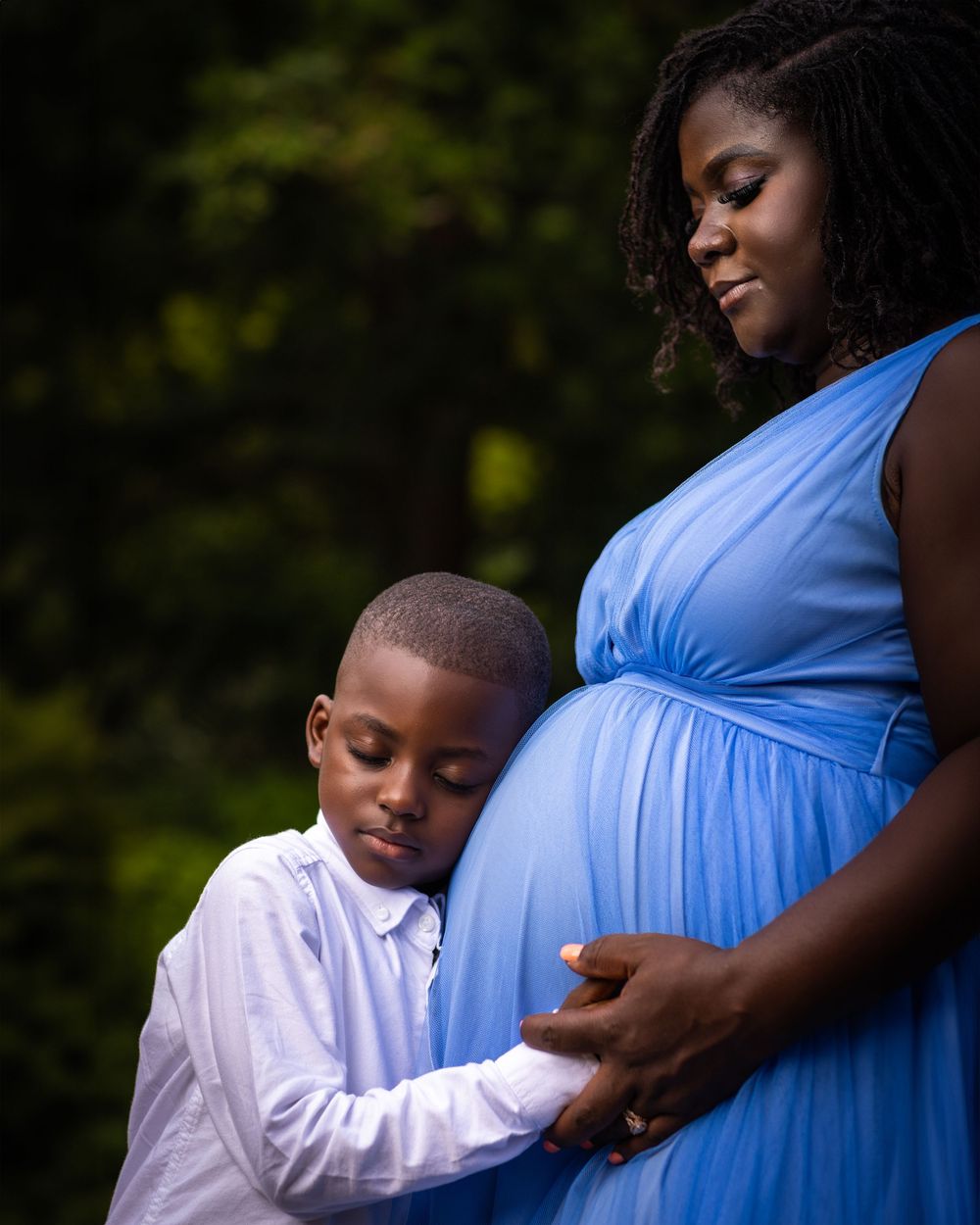 A touching moment captured in soft focus showing a gentle embrace with a light blue maternity dress.
