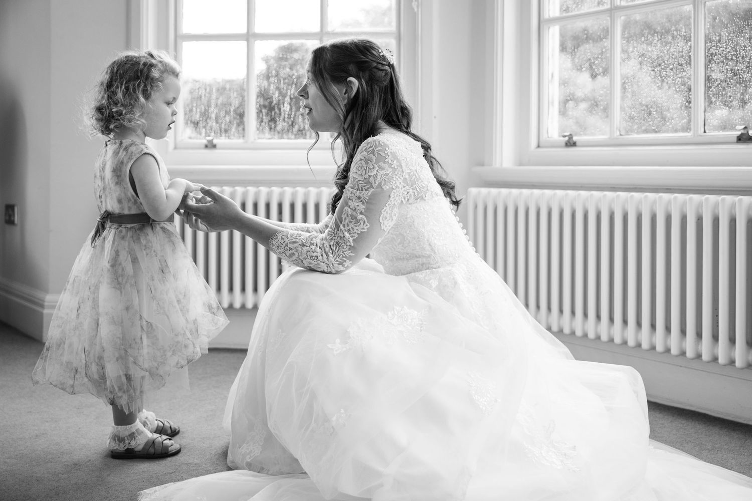Bride kneeling to greet a young child in the Bridal Suite at Kelham House