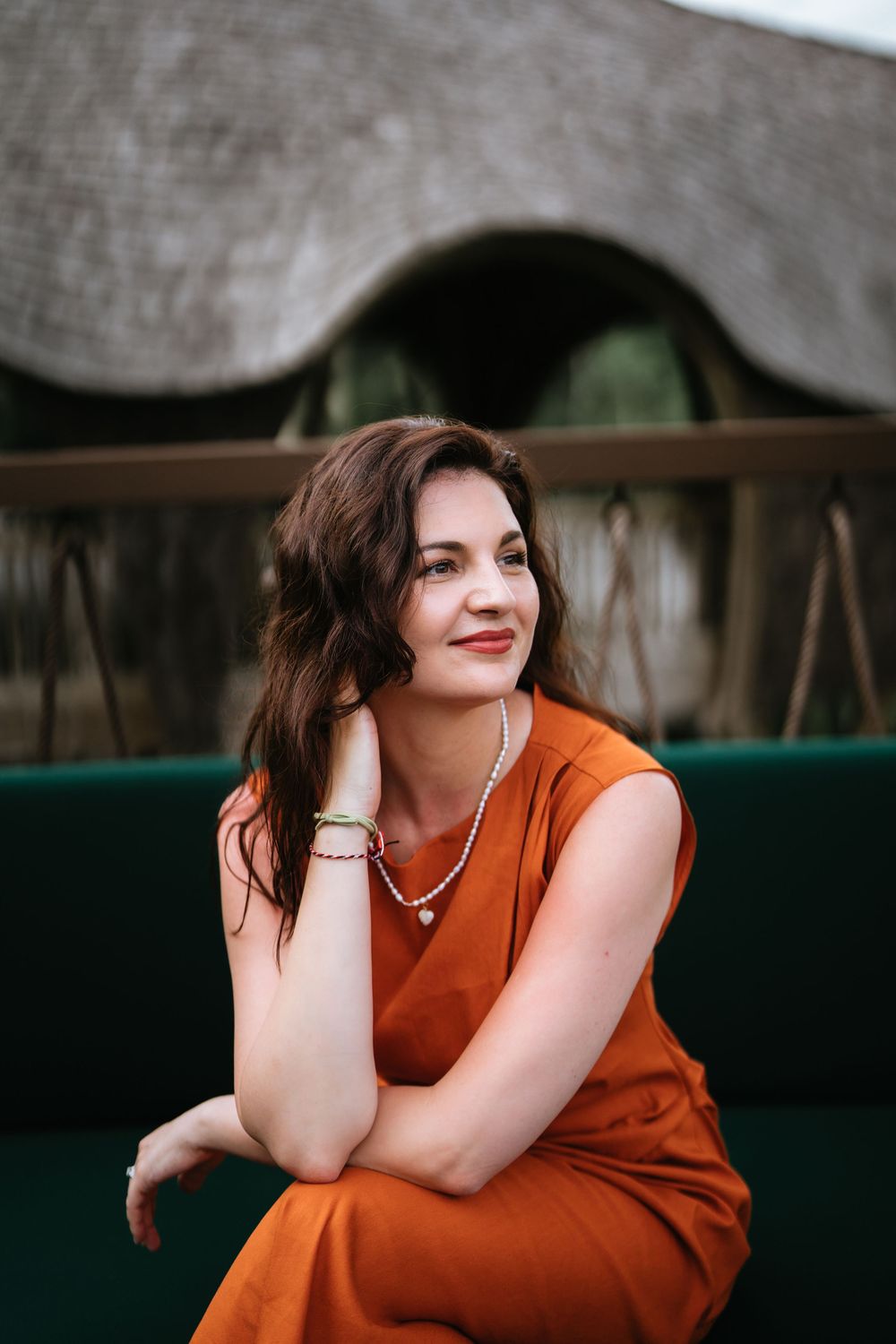 A casual portrait featuring an orange dress against a dark interior setting.