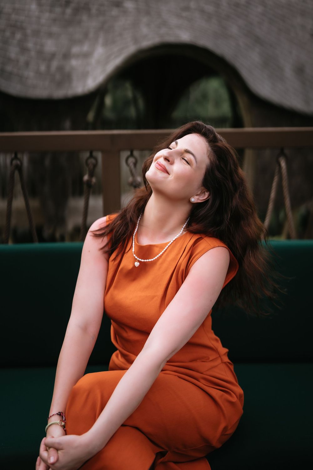 Candid moment captured in an orange dress against rustic decor.