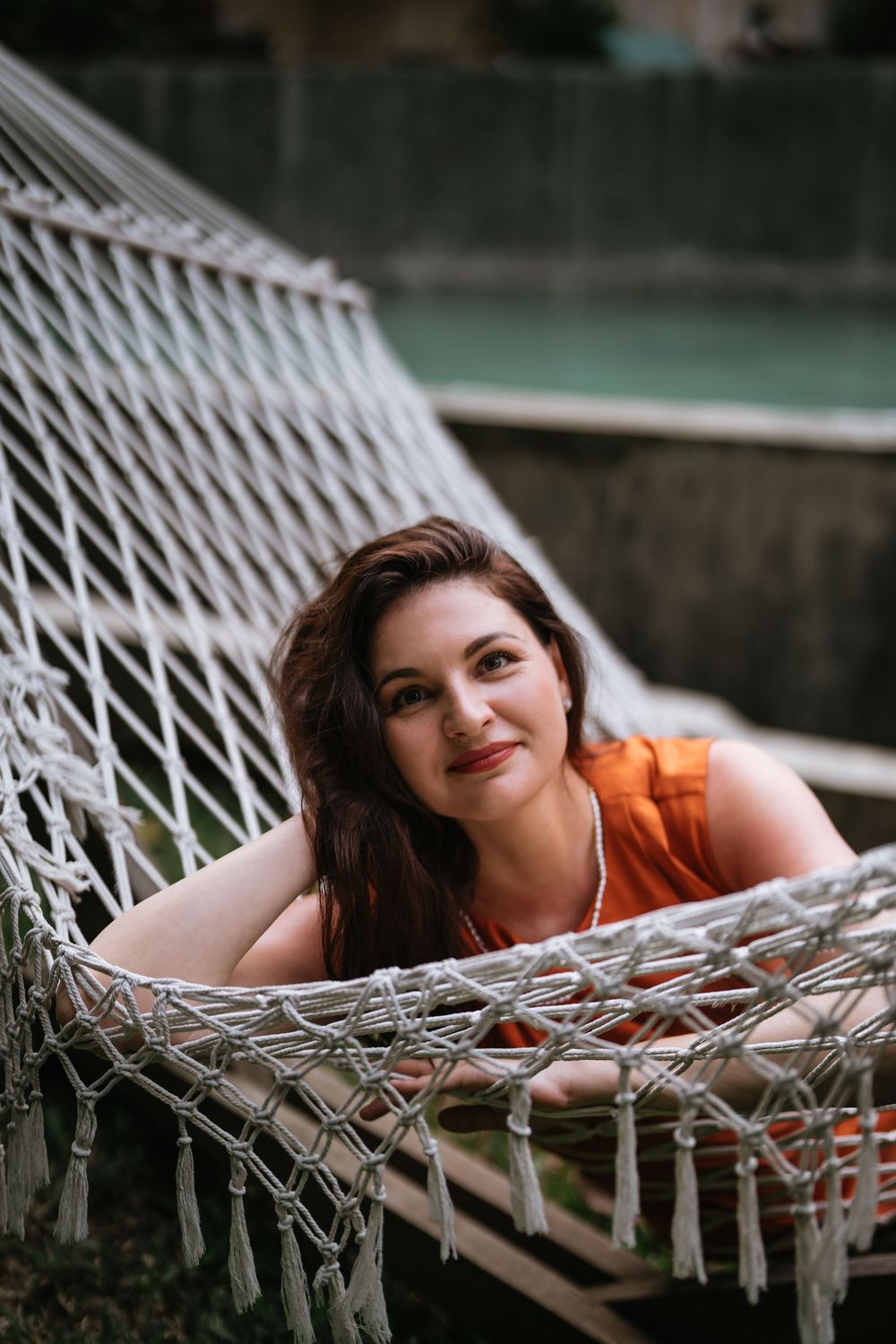 Resting peacefully in a white hammock wearing a vibrant orange dress.