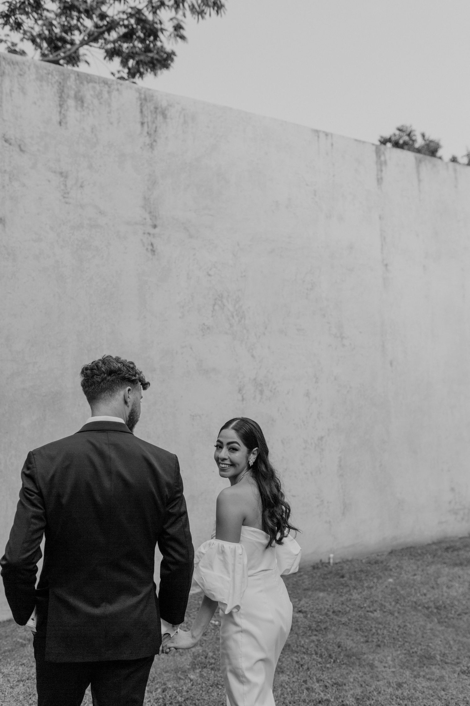 Black and white portrait of couple in wedding attire walking together.