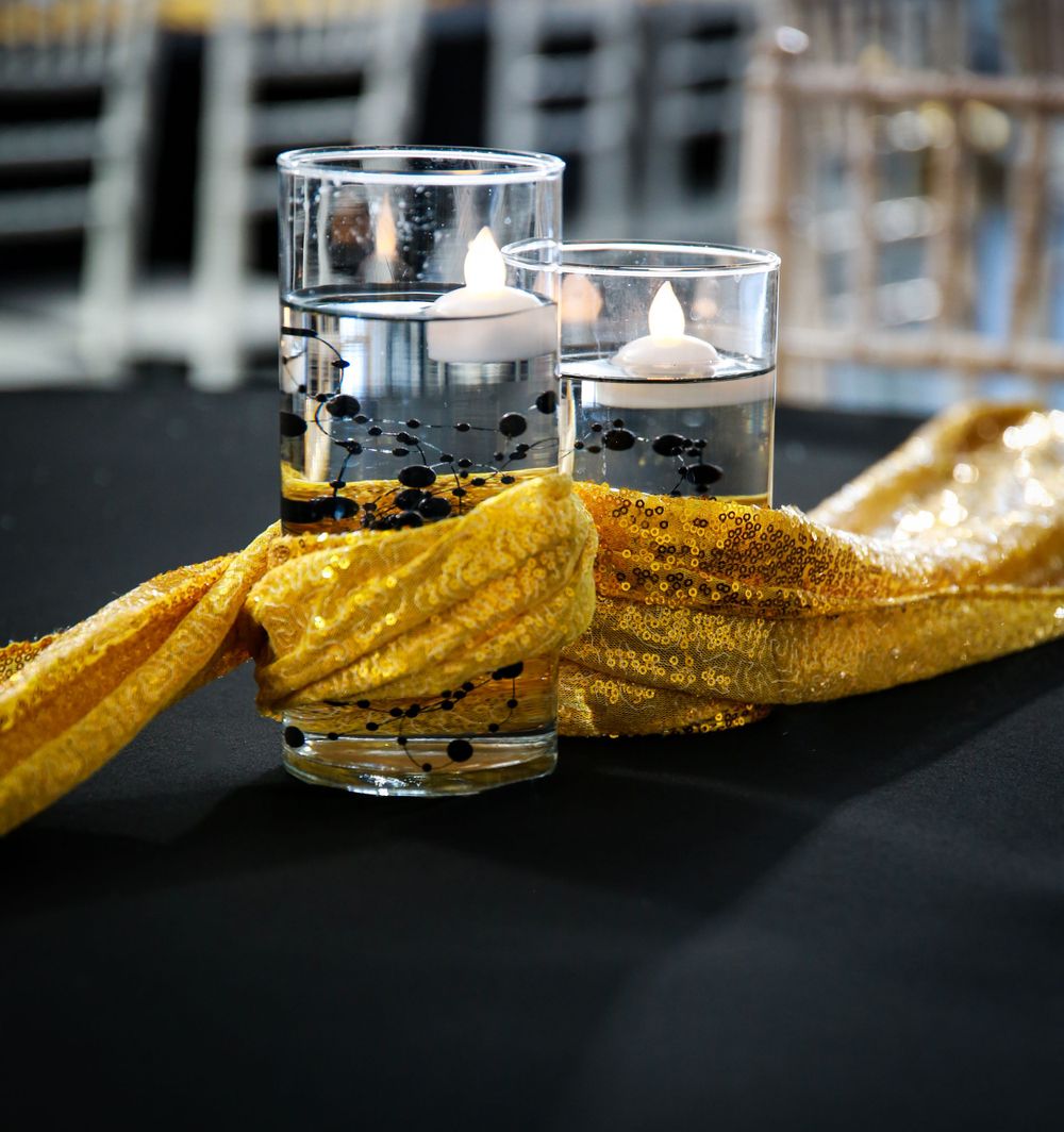 Two glasses filled with clear liquid sit beside a crispy grilled yellow sandwich on a dark surface.