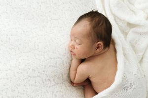 Dolce neonato che dorme pacificamente su uno sfondo bianco strutturato. nel mio studio a Cassine AL.