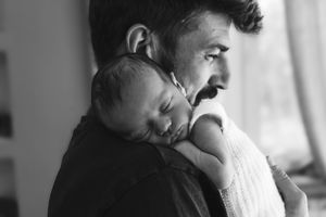Ritratto in bianco e nero di un neo papà con la sua bimba appena nata, a domicilio a casa loro.