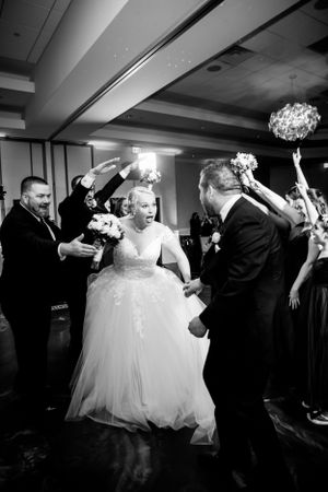 Wedding reception dance floor celebration with bride in white gown surrounded by guests.