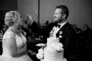 Wedding cake cutting moment captured in black and white photography.
