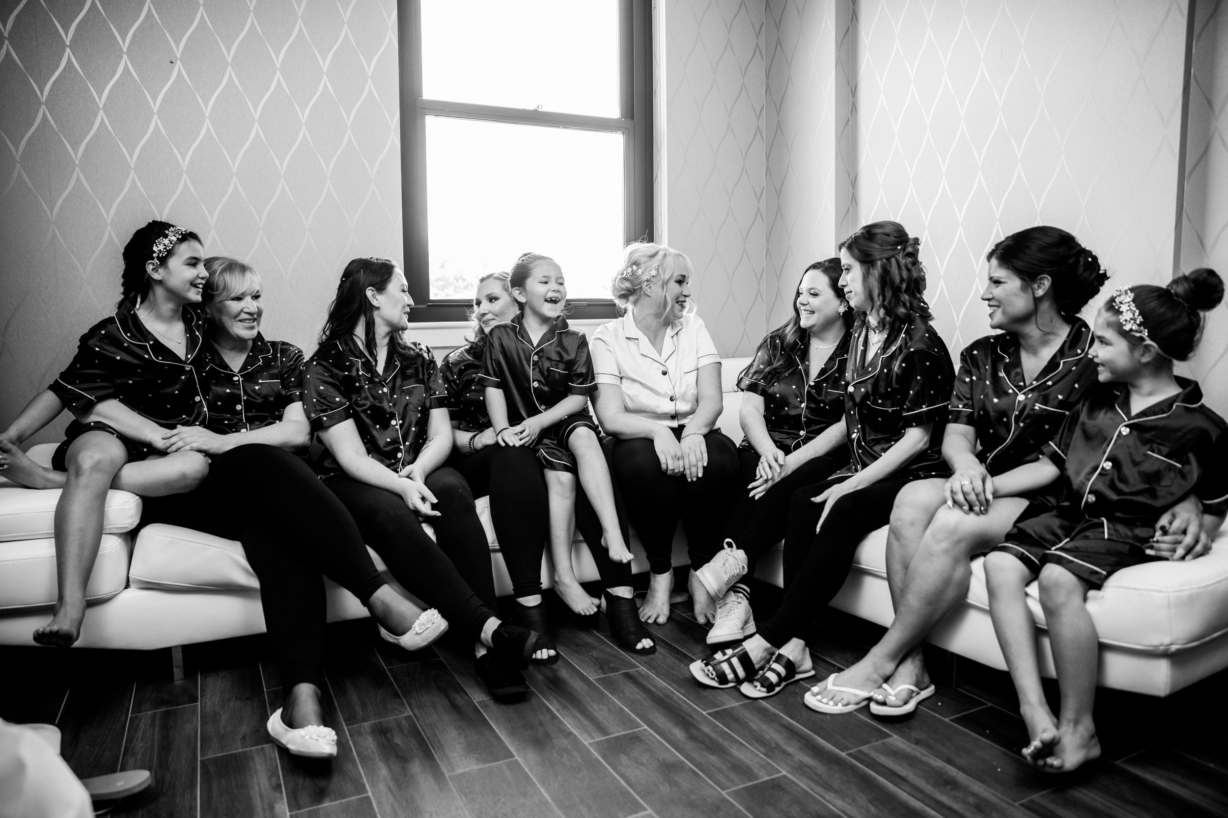 A group of wedding guests sitting together on a couch having an animated conversation.