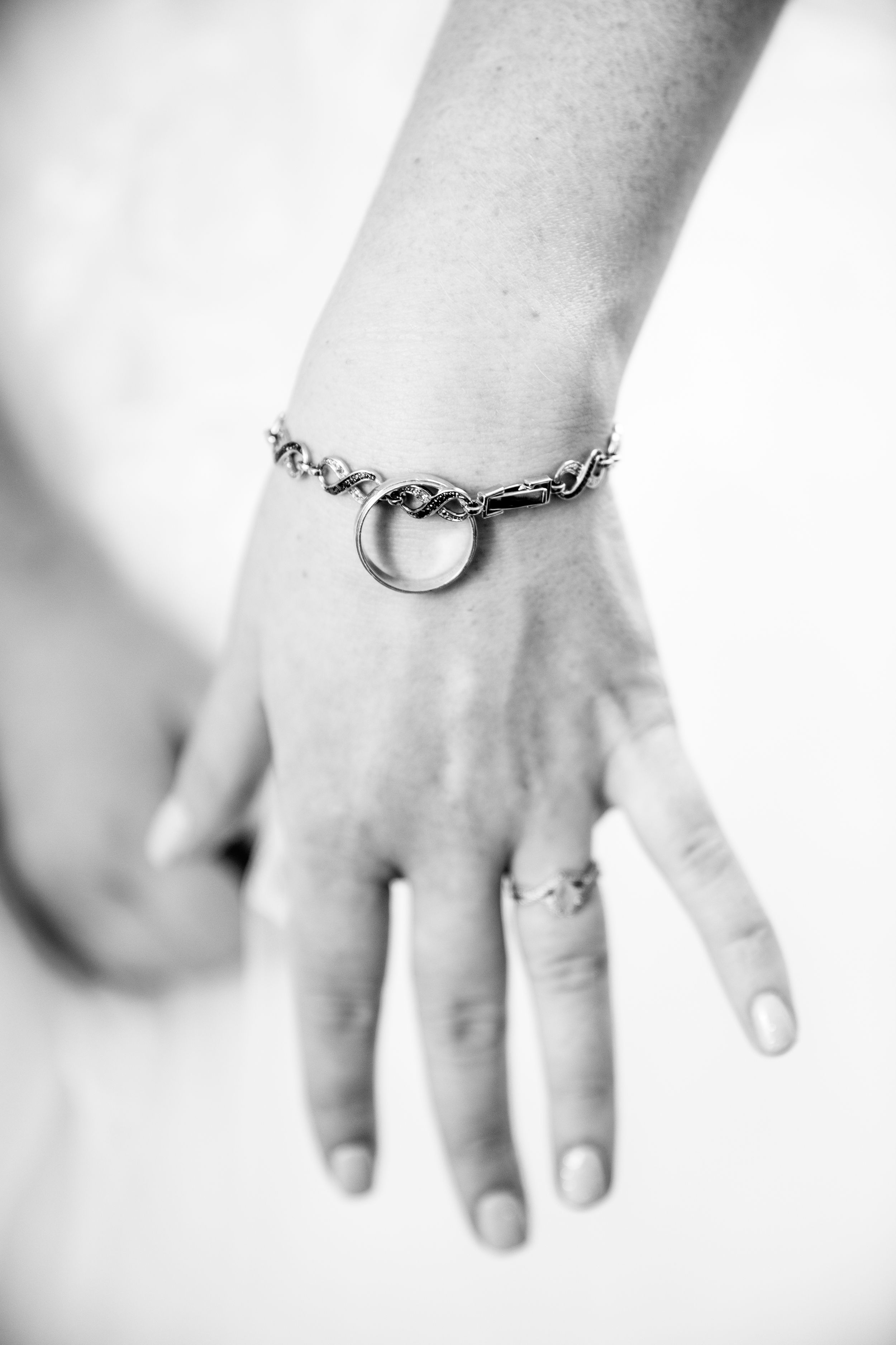 A delicate chain bracelet with a heart charm adorns a hand in black and white.