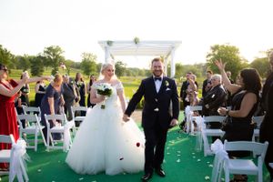 Wedding ceremony exit with bride and groom walking down outdoor aisle.