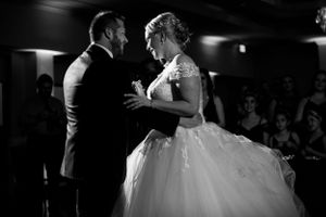 Couple sharing their first dance at a wedding reception in dramatic lighting.
