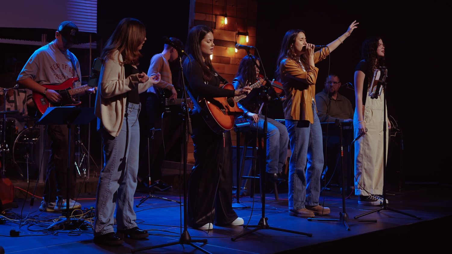 Musicians performing on stage with dramatic blue lighting and instruments.
