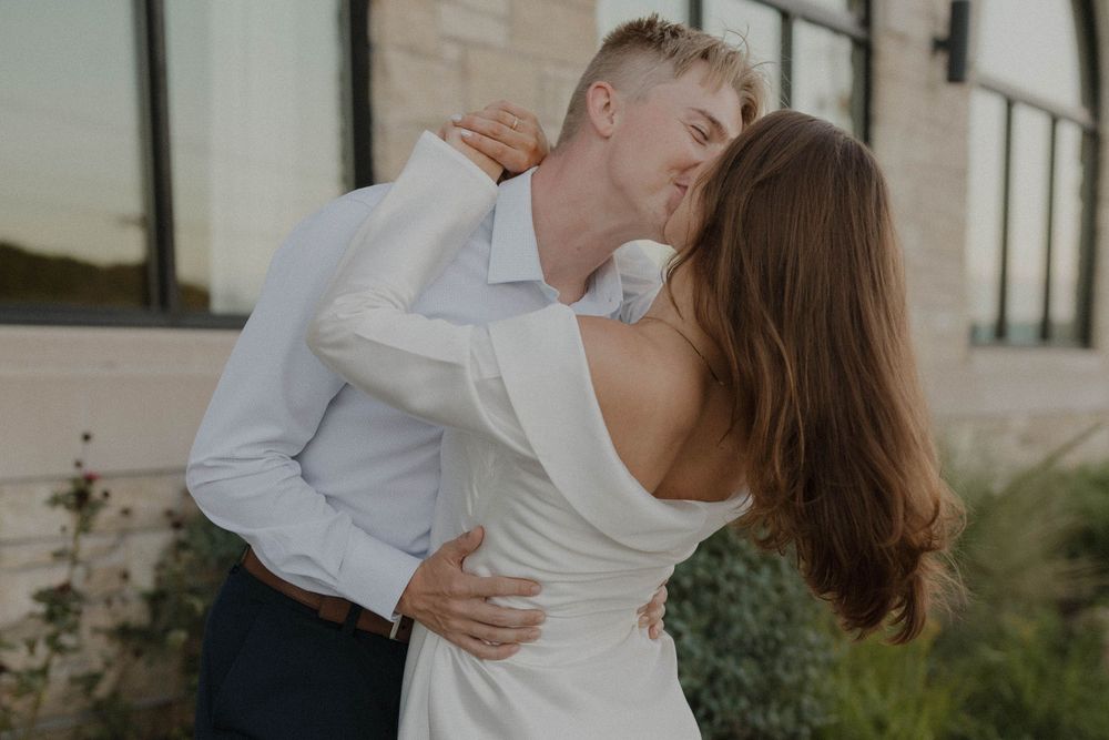 An intimate embrace photographed against a modern architectural backdrop.