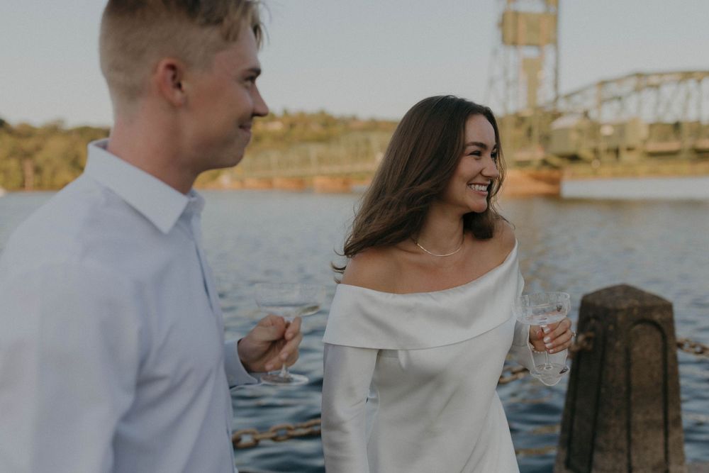Couple sharing a romantic moment by the waterfront with industrial backdrop.