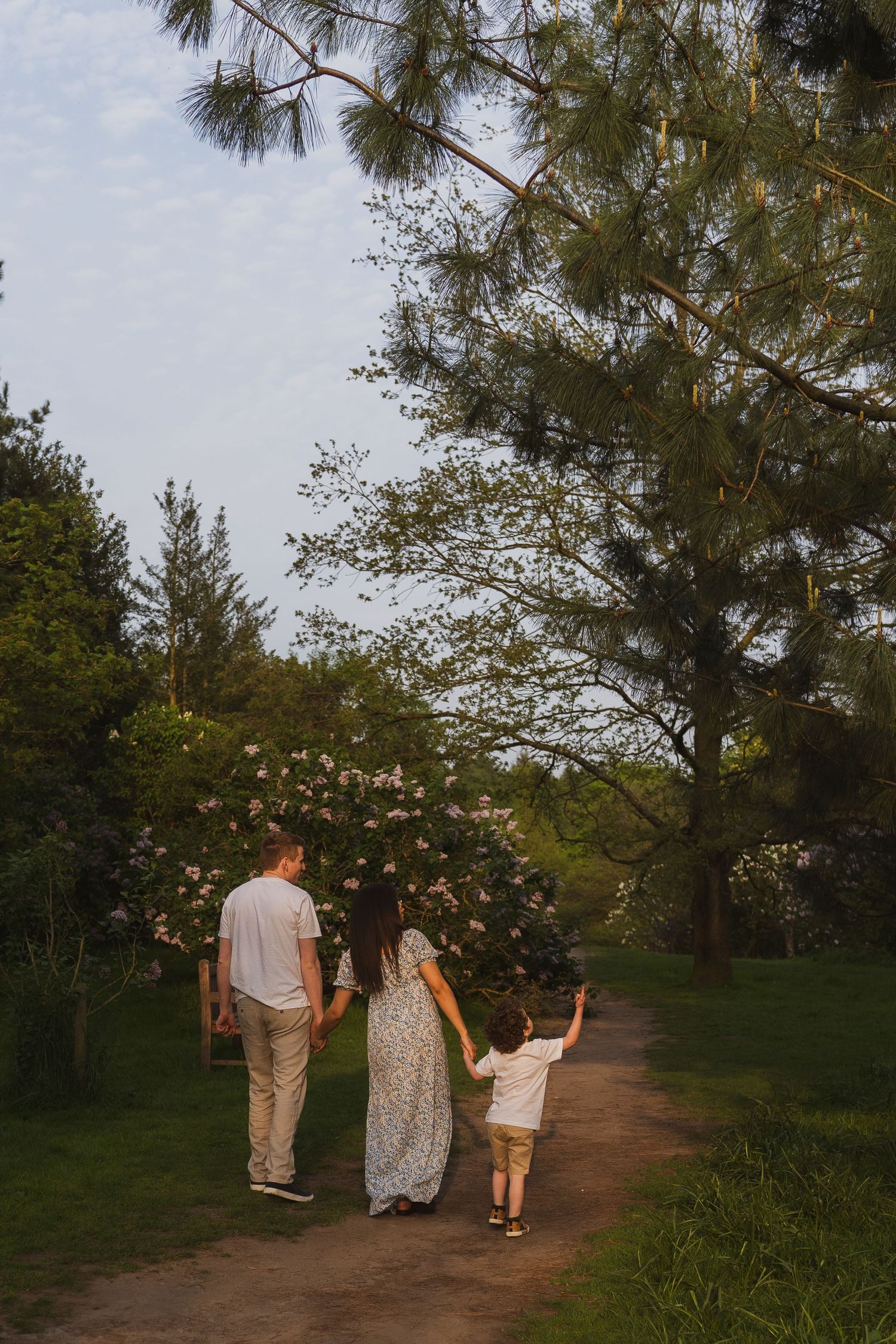 A family walking together on a tree-lined path during golden hour during their maternity session at Golden Acre Park.