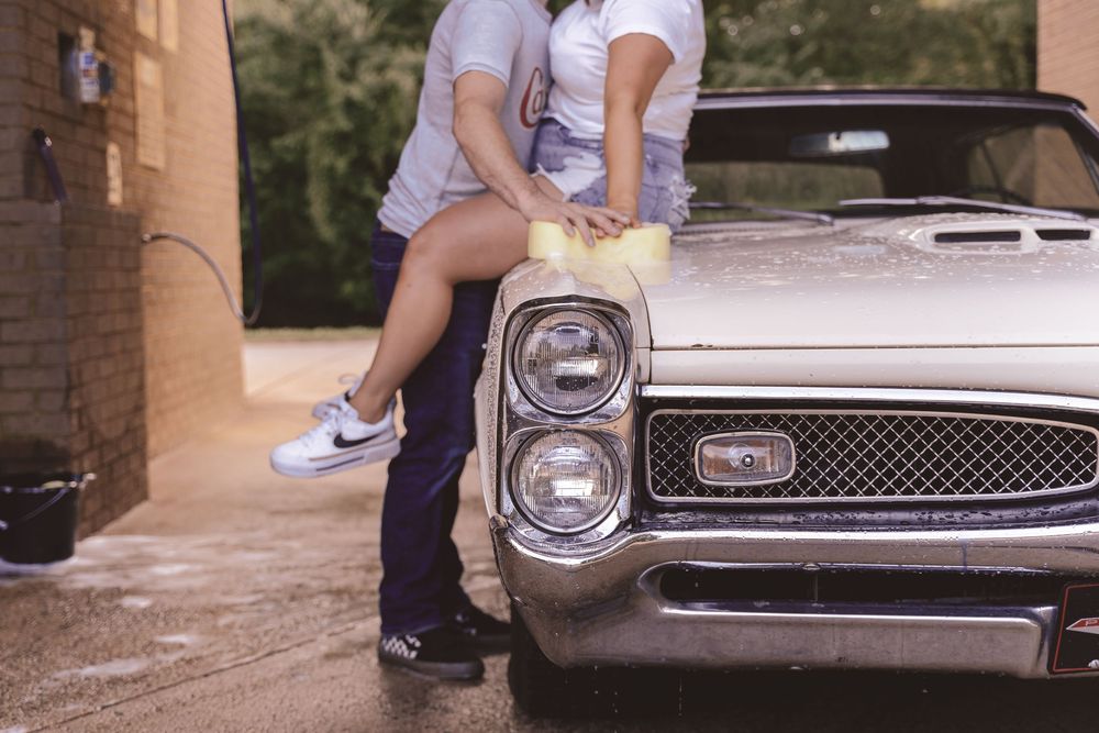 Candid lifestyle couples photo featuring a couple washing a vintage car