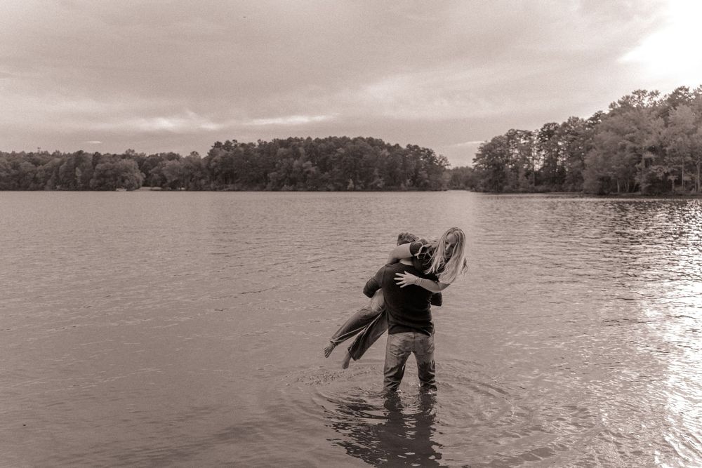 Couple playfully swinging during a couples lifestyle session at the lake in Charlotte, North Carolina