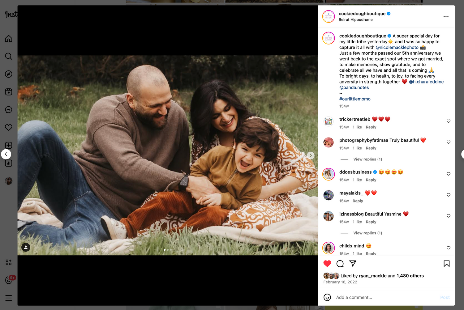 A family lounging together on a blanket outdoors with their son on a sunny day.