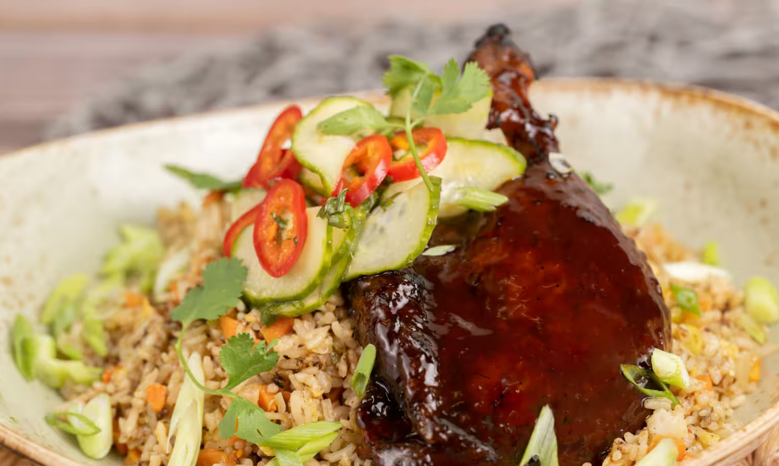 Glazed Asian braised pork belly with spicy chili garnish served over fragrant rice and fresh greens.